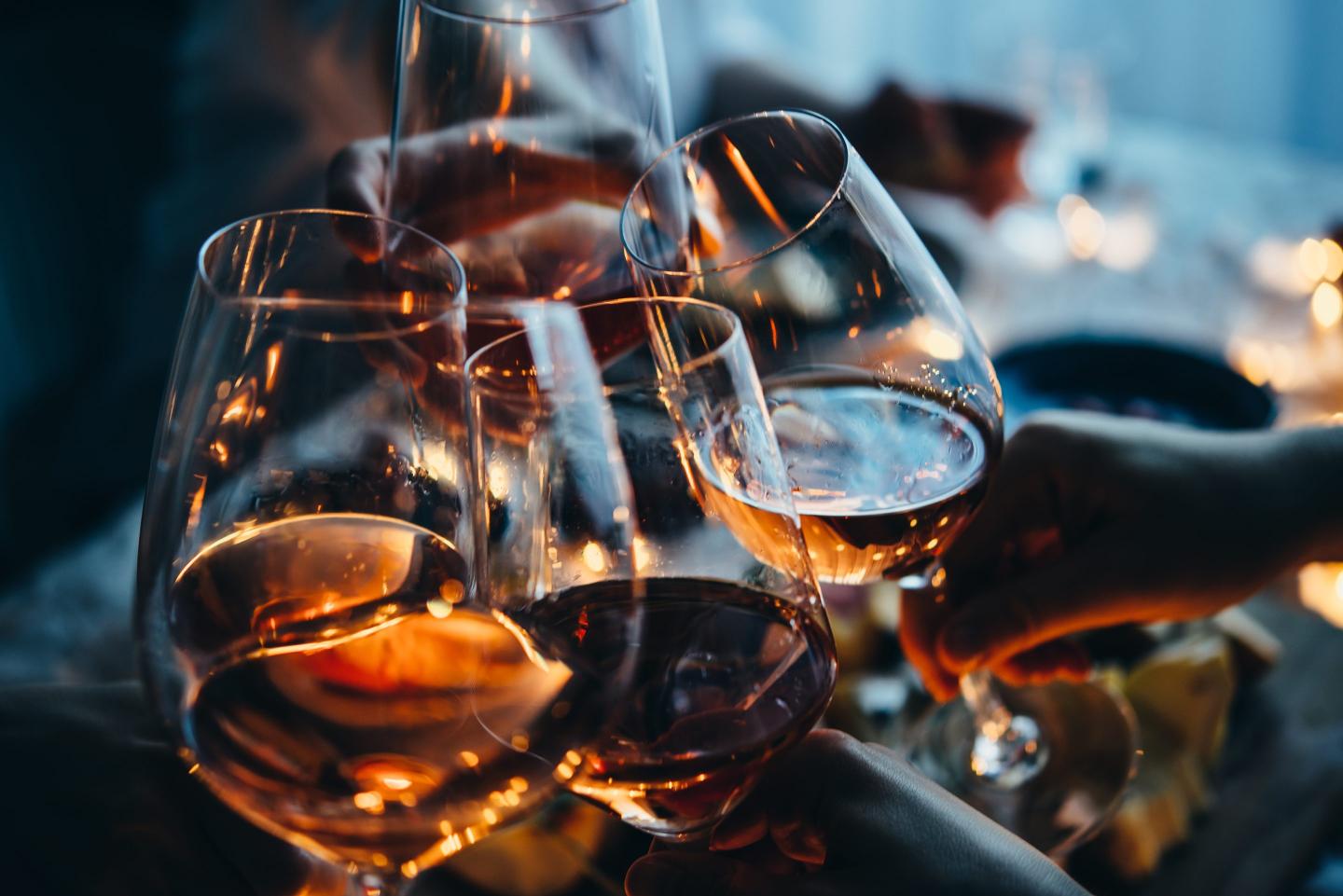 People clink wine glasses at a dinner party