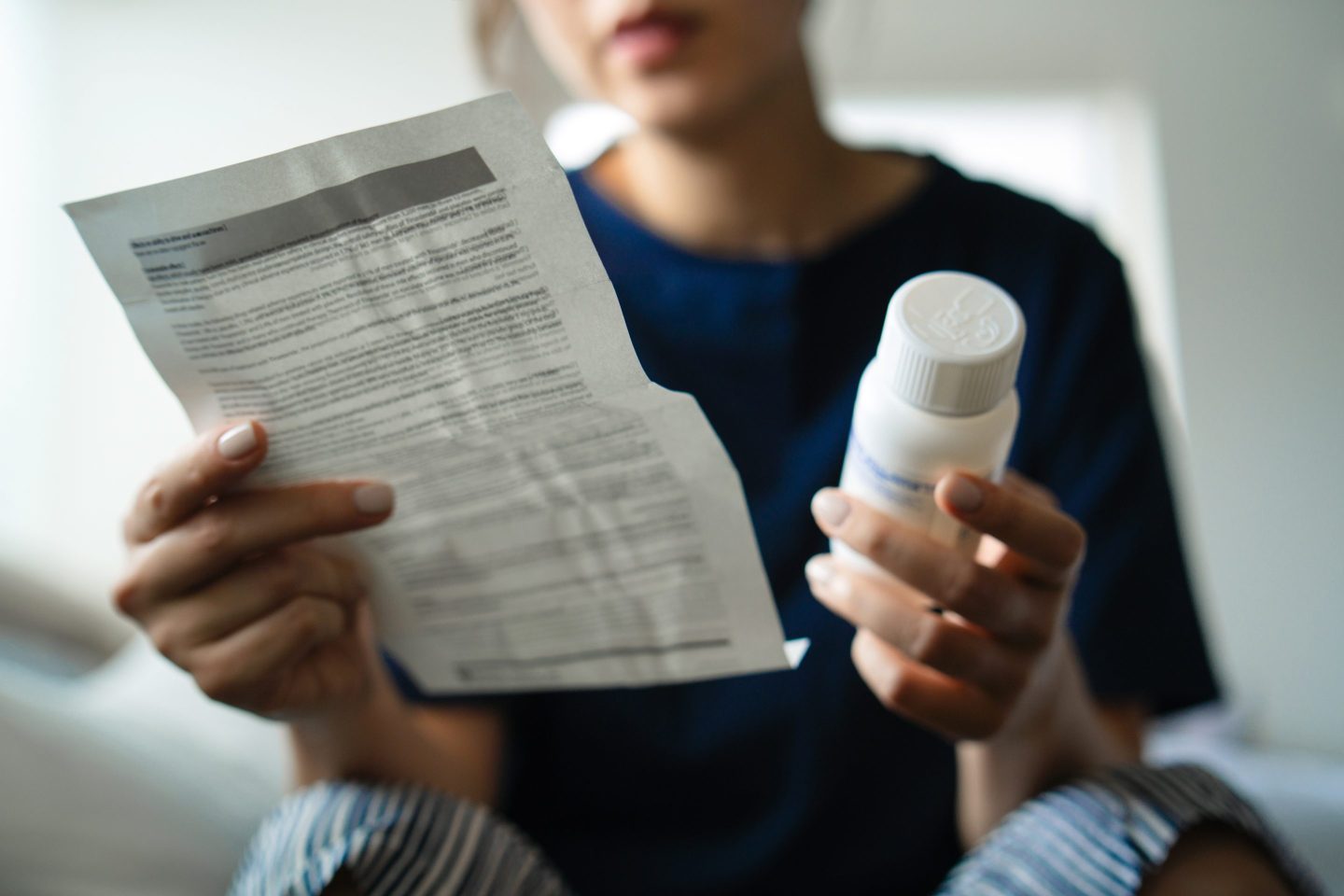 A woman holds a medicine bottle while reading instructions.