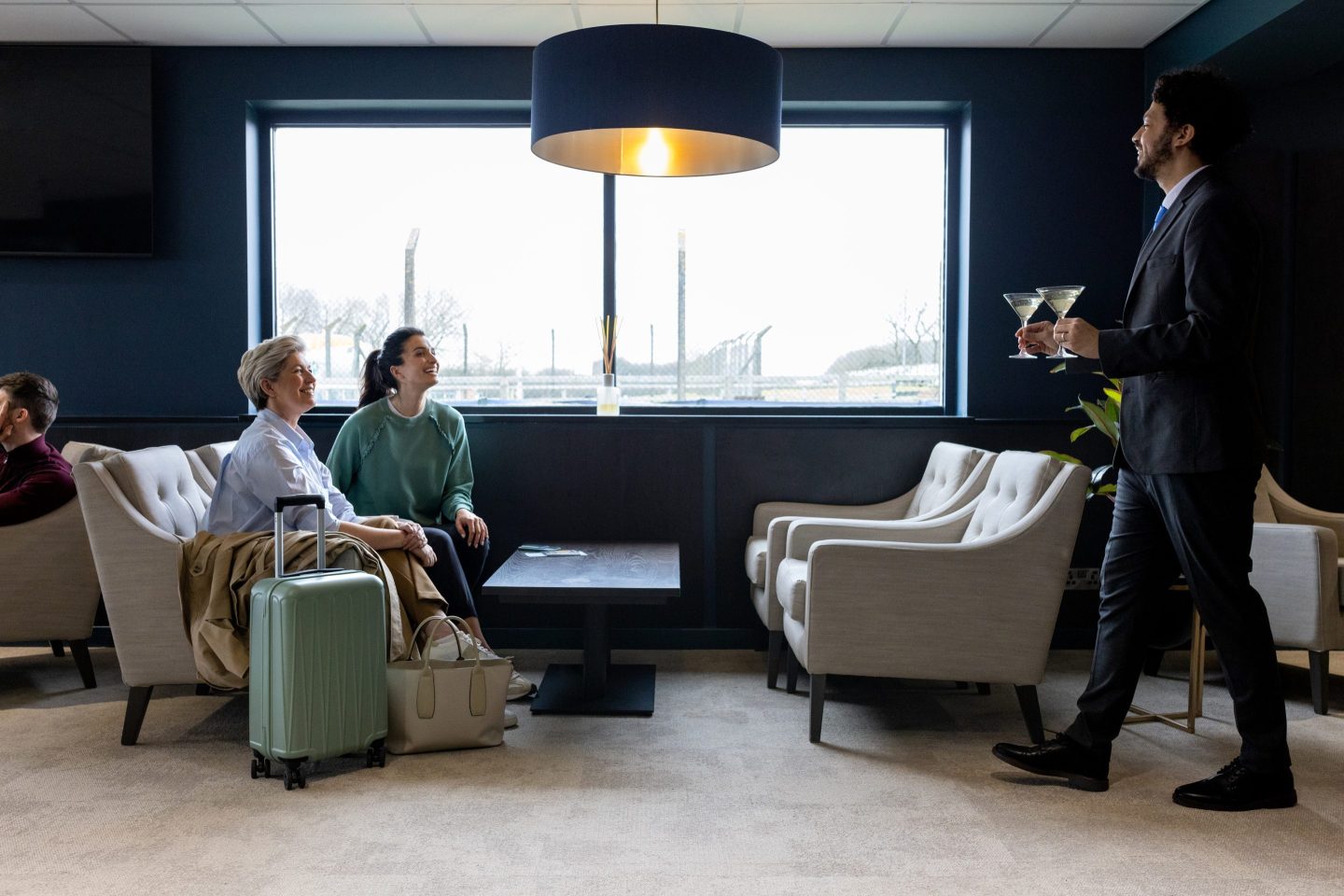 Server carrying two martinis past people on a couch.