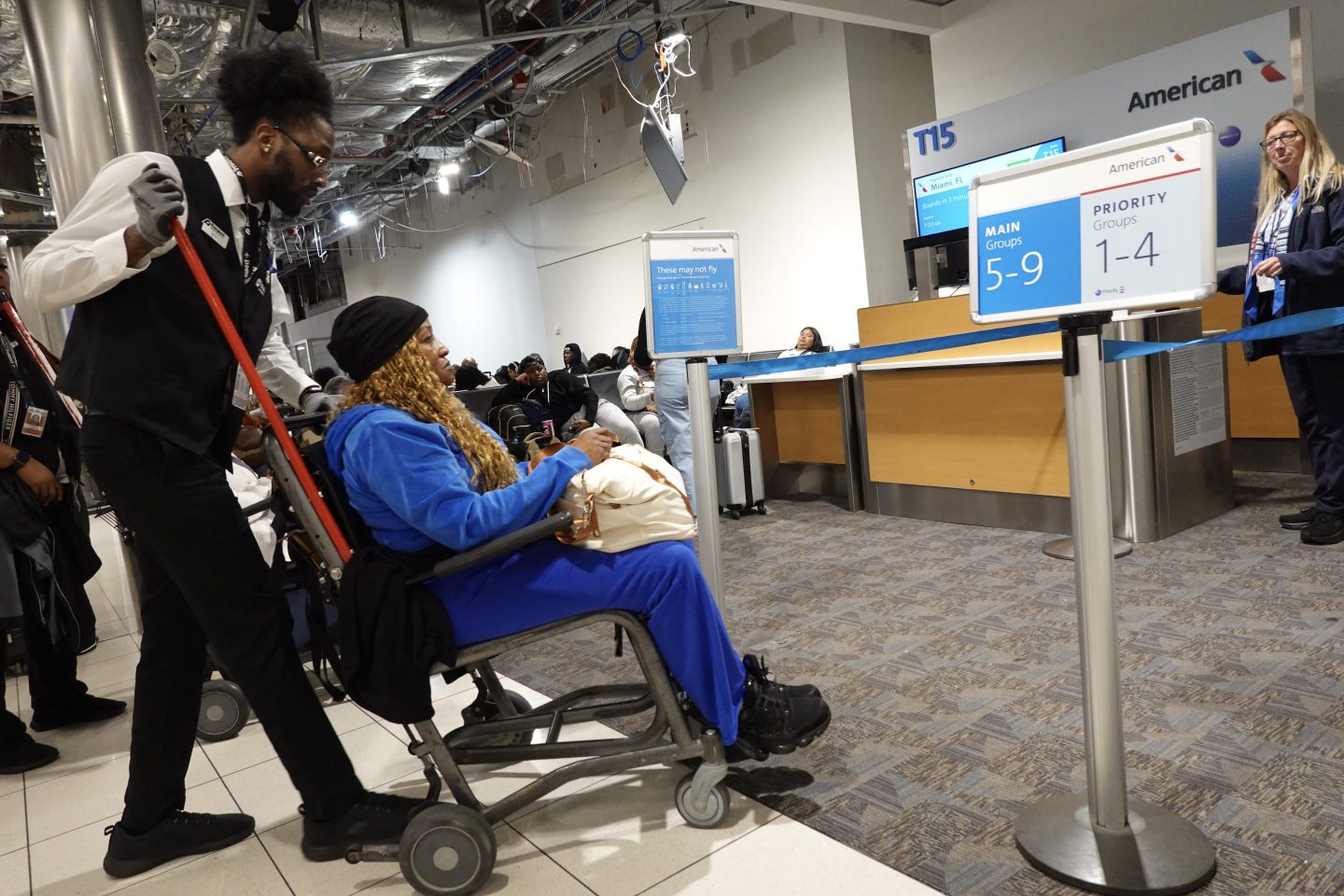 A person pushes a woman in a wheelchair to an airport gate.