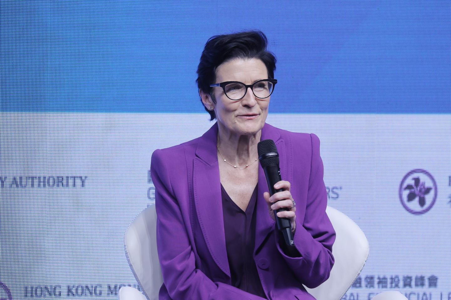 Jane Fraser in a purple suit sitting on a stage
