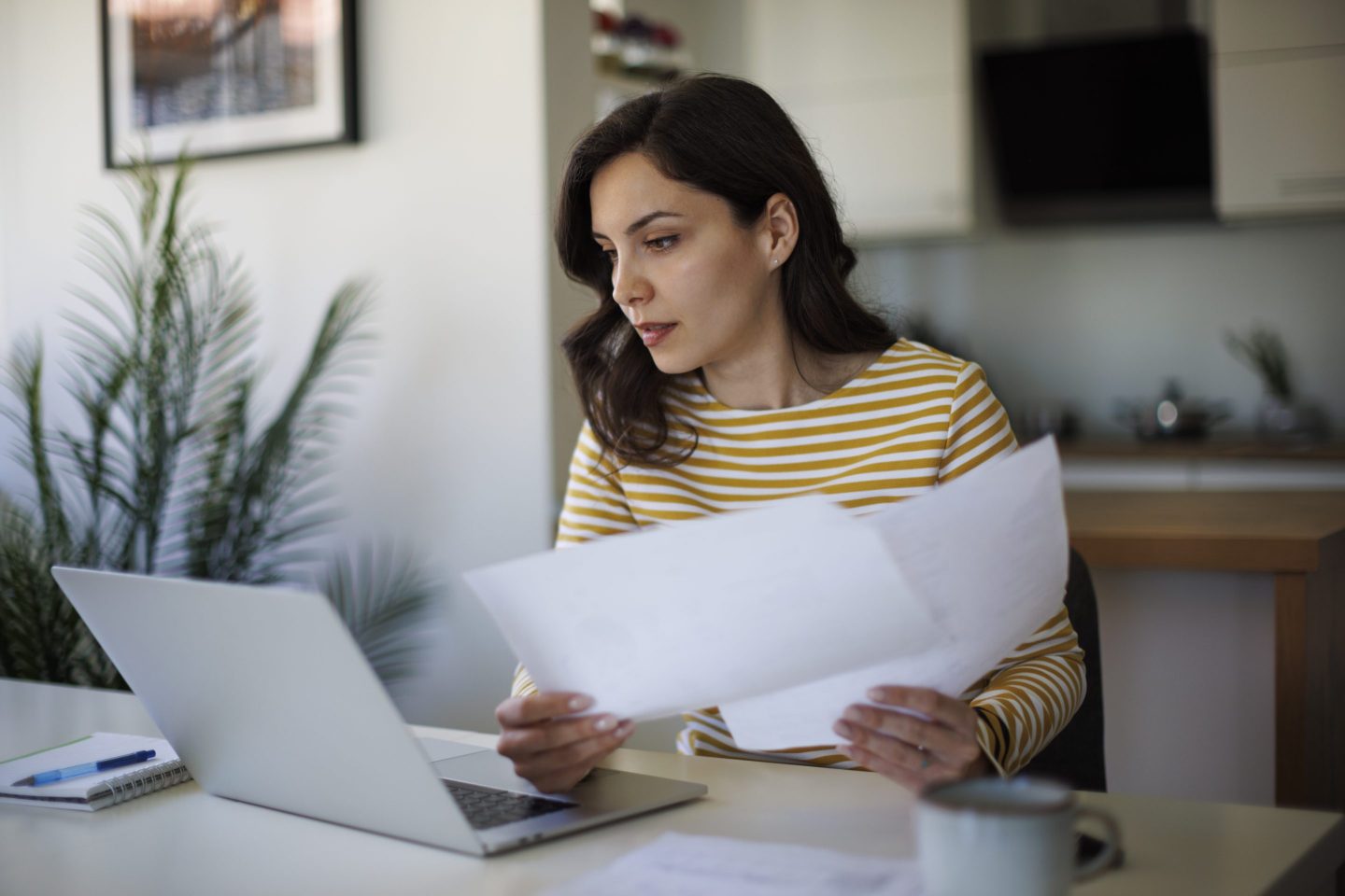 A person holding a pile of forms looking at their computer.