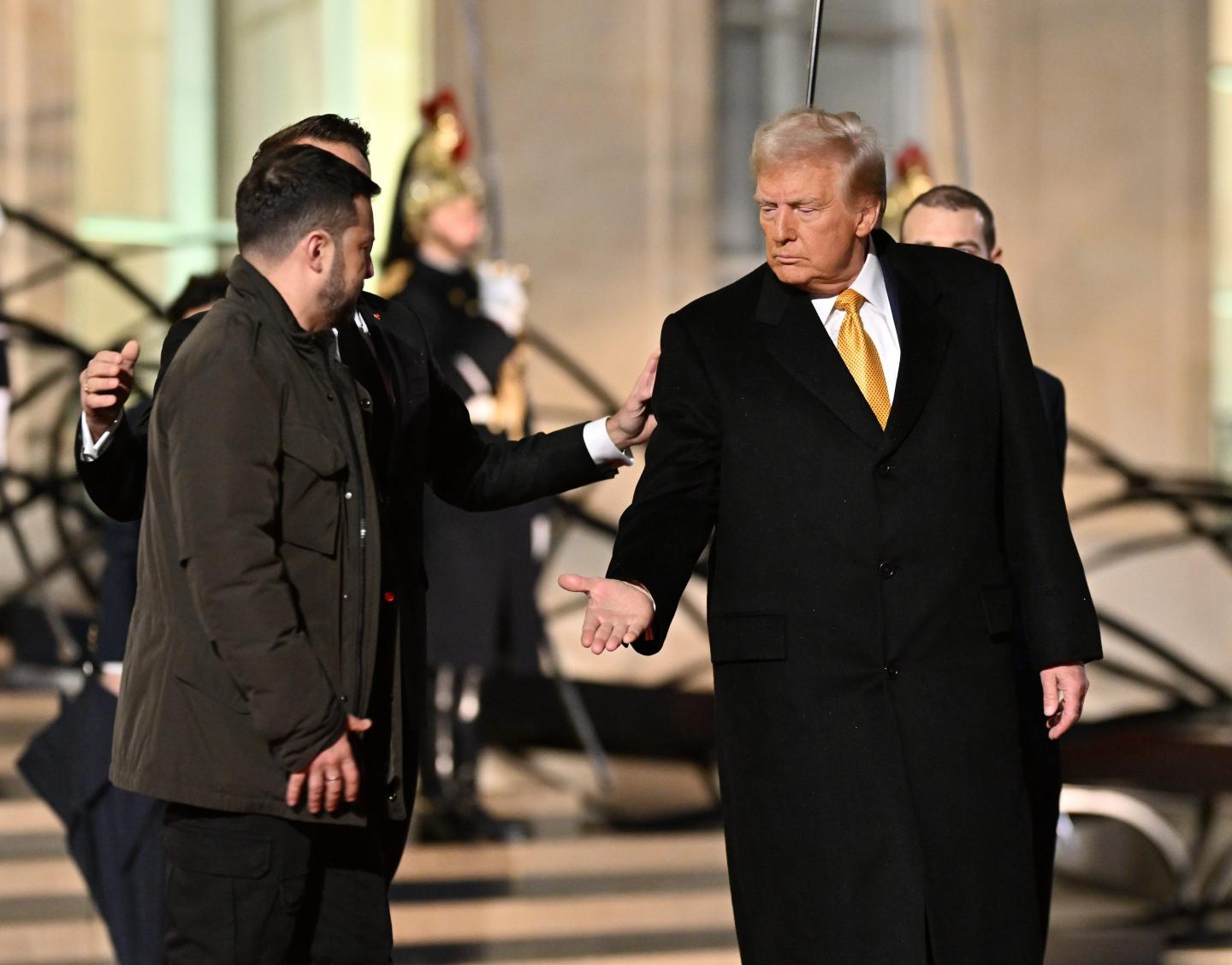 Donald Trump puts out his hand as Volodymyr Zelenskyy prepares to shake it.