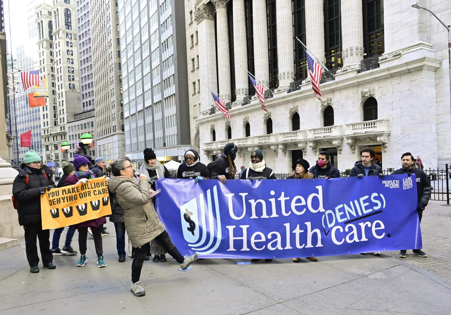 Protesters hold a sign saying, "United denies Health Care"