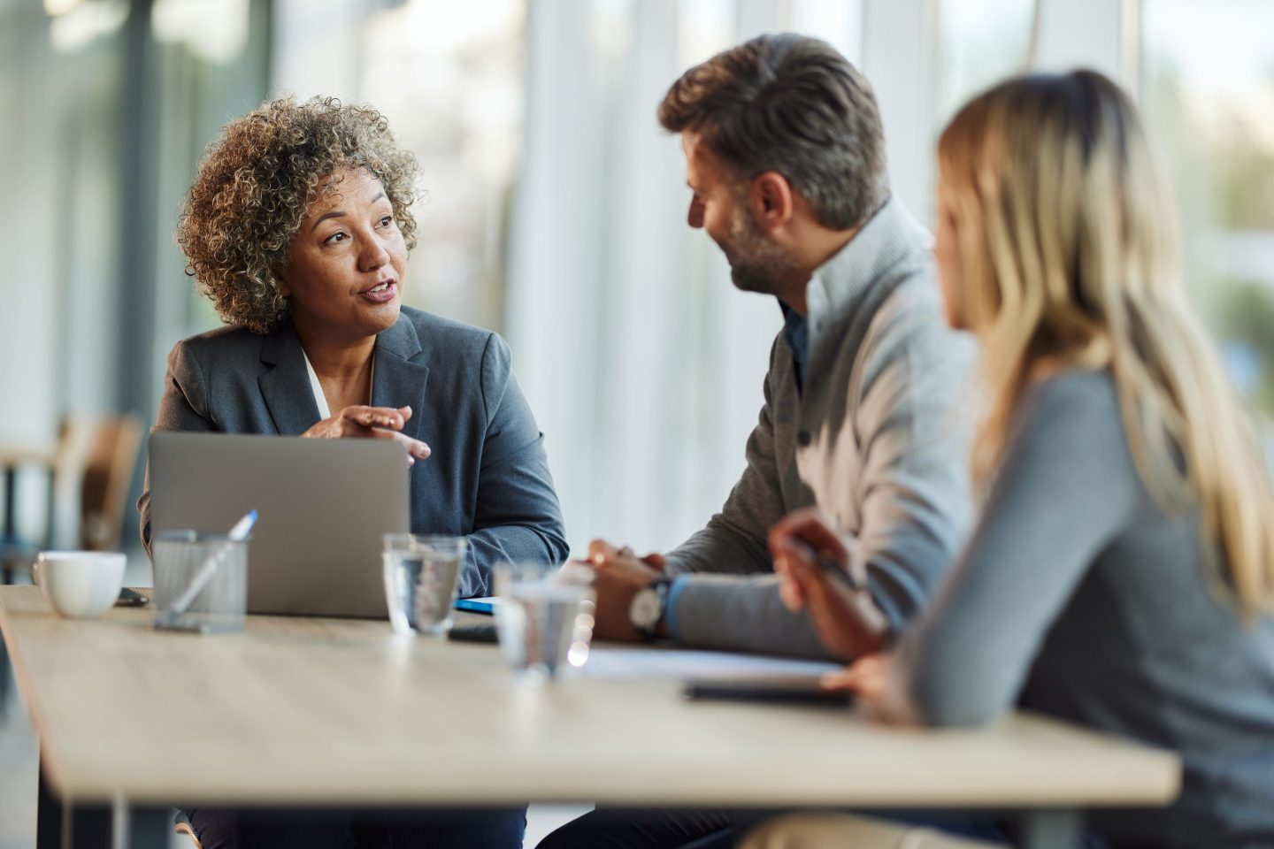 Businesswoman communicates with two clients sitting at a table
