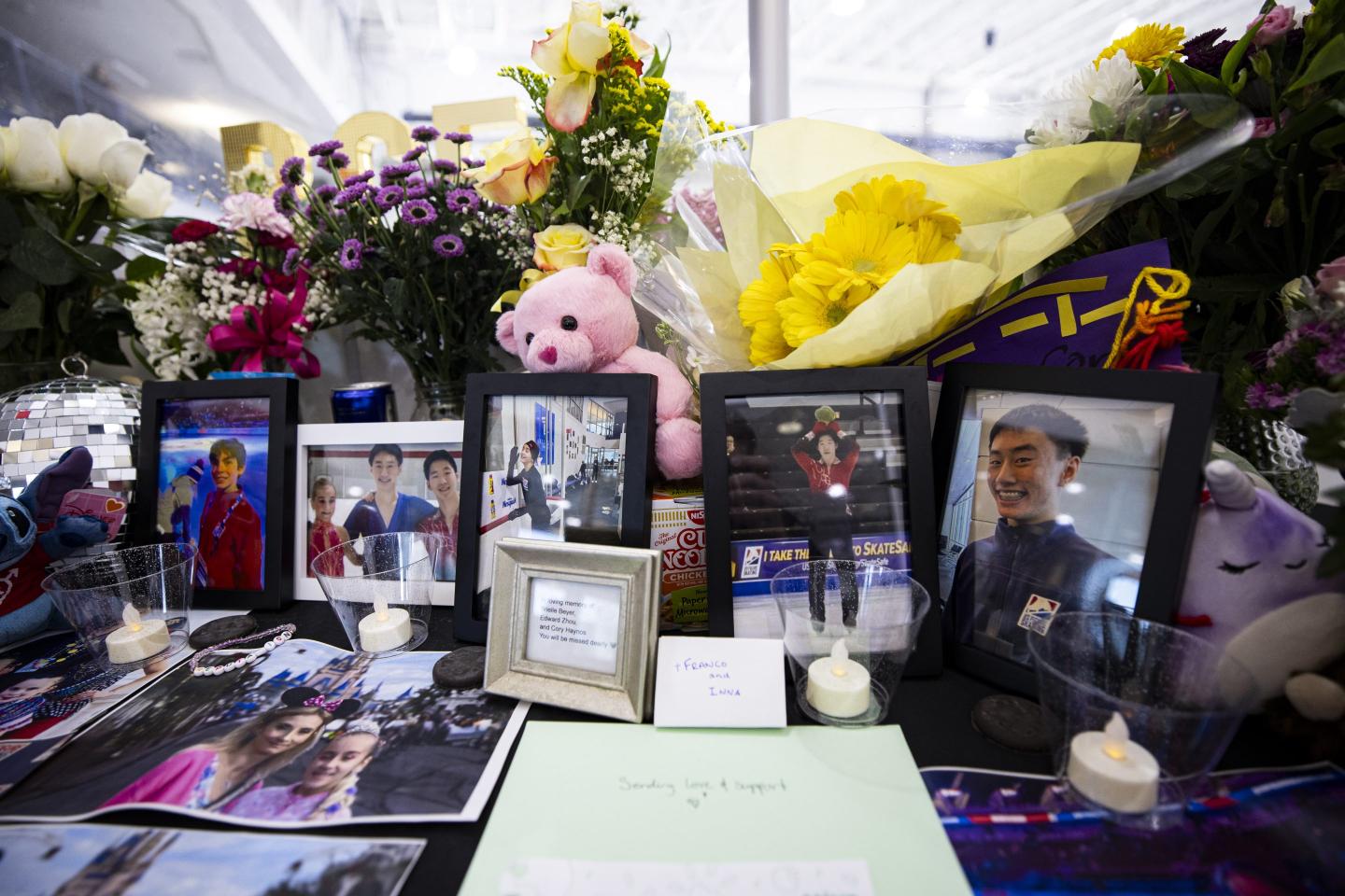 A table holds a memorial with photos and flowers to remember those who died on the American Airlines flight that collided with a Black Hawk helicopter