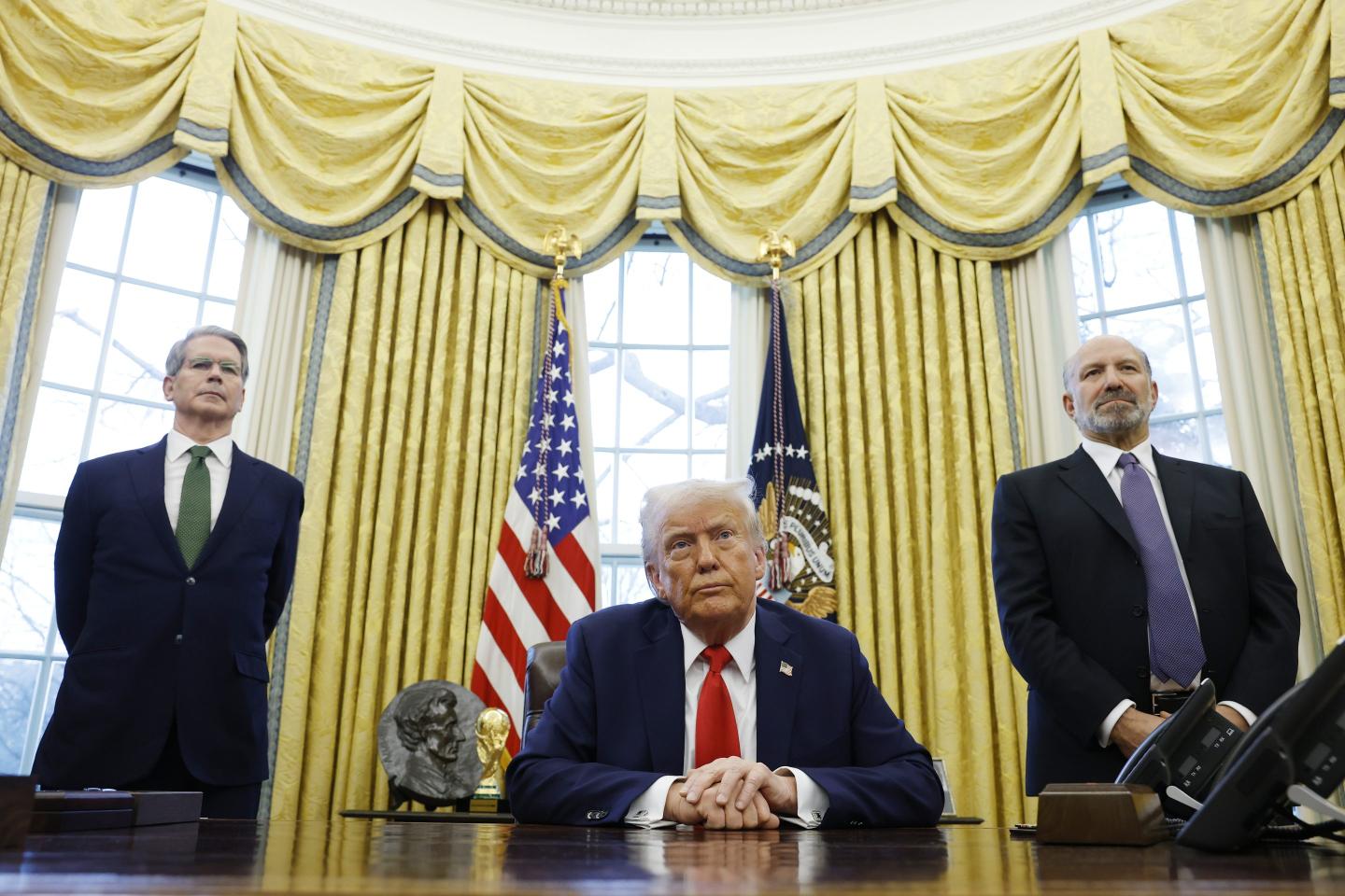 U.S. Secretary of Treasury Scott Bessent (L) and Howard Lutnick, U.S. President Donald Trump's nominee for Commerce Secretary, (R) stand behind U.S. President Donald Trump as he speaks to reporters in the Oval Office of the White House on February 03, 2025 in Washington, DC.