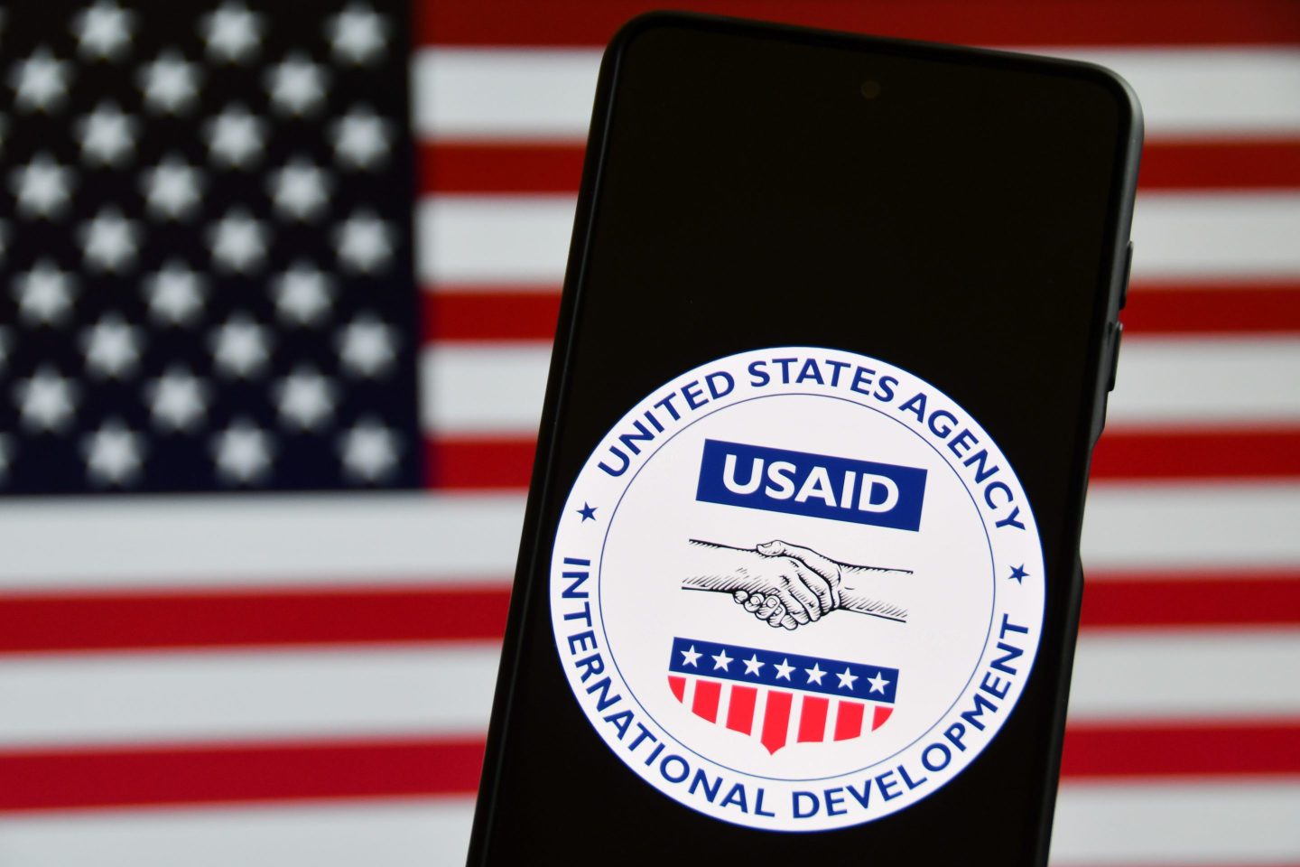 The United States Agency for International Development (USAID) emblem is screened on a mobile phone