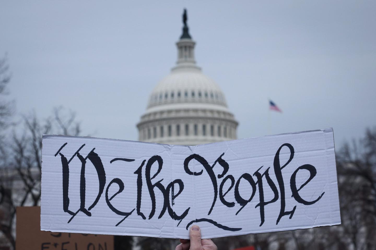 U.S. Capitol building with a sign that reads "We the People" in front of it