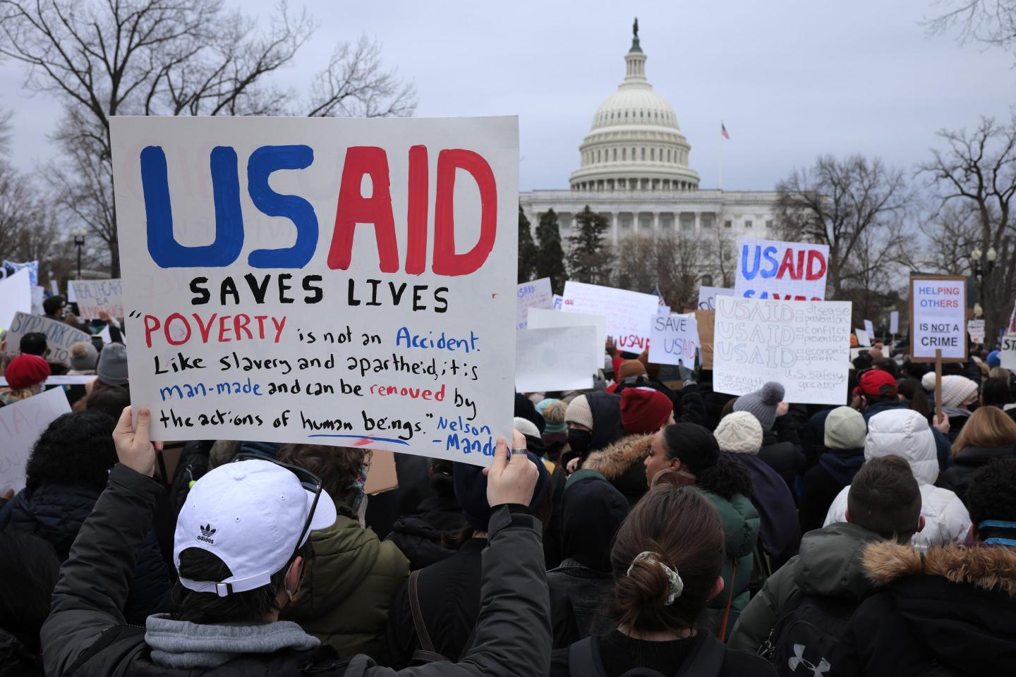 People hold up signs while rallying for USAID
