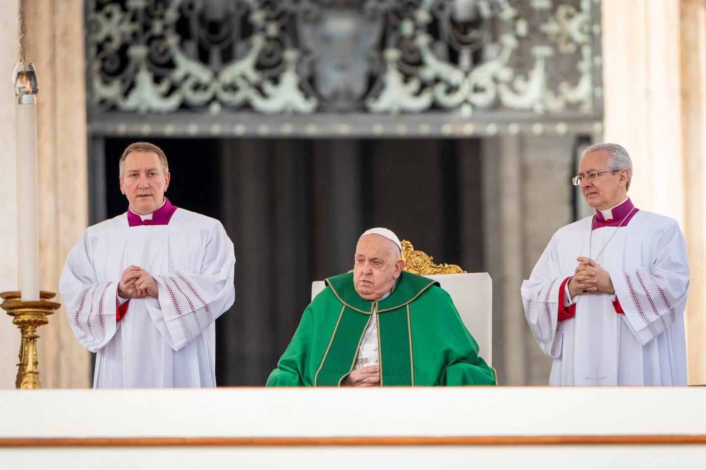 Pope Francis is bookended by two bishops clasping their hands together