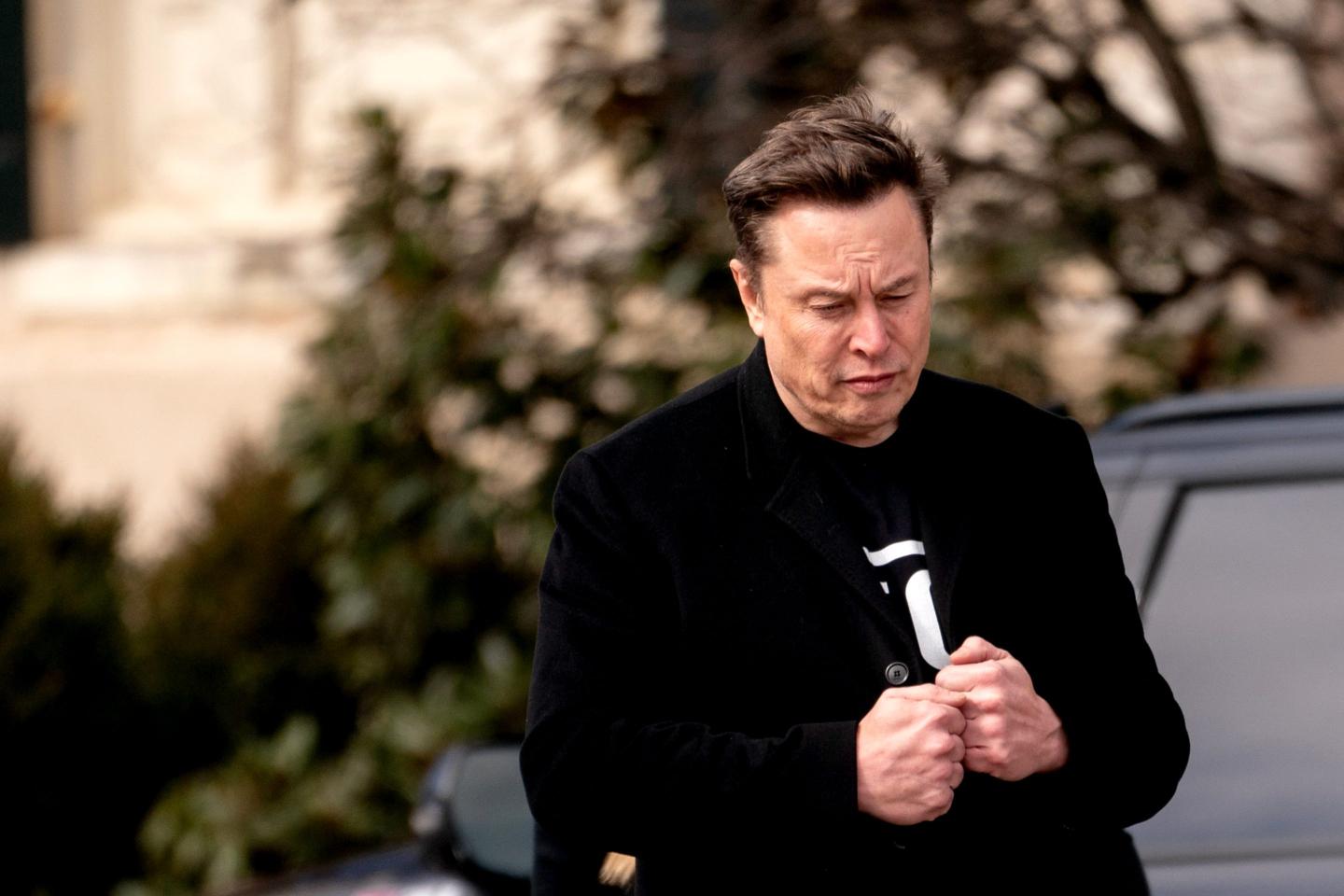 Elon Musk, chief executive officer of Tesla Inc., looks down and puts his hands together as he walks to the Eisenhower Executive Office Building (EEOB) near the White House in Washington, DC, US, on Thursday, Feb. 13, 2025.