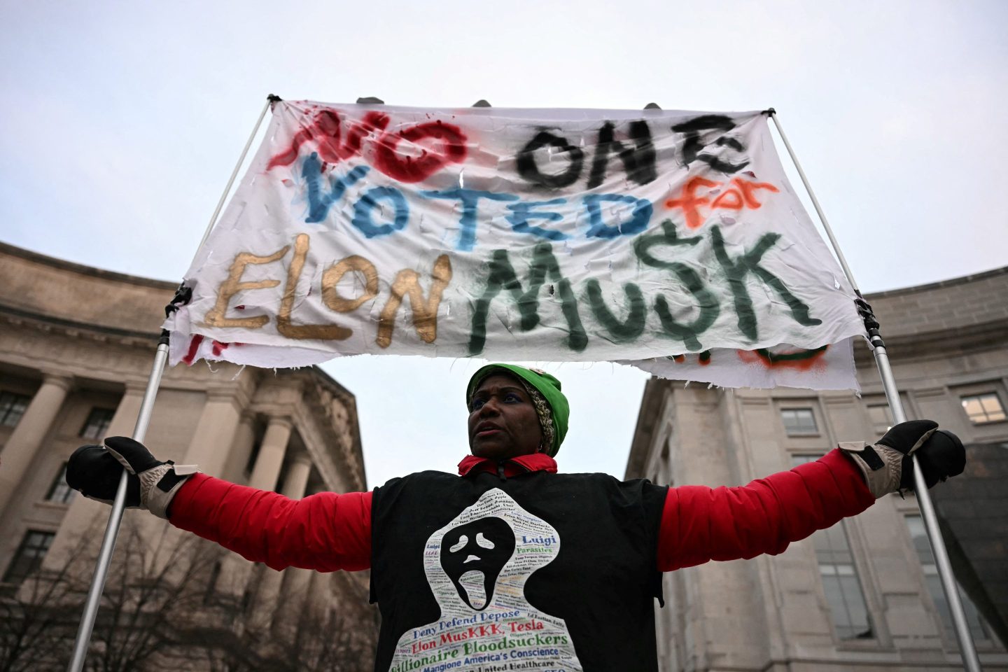 A protestor holds a banner during a demonstration against the policies of US President Donald Trump and Elon Musk's Department of Government Efficiency (DOGE) near Musk's SpaceX headquarters in Washington, DC, on February 19