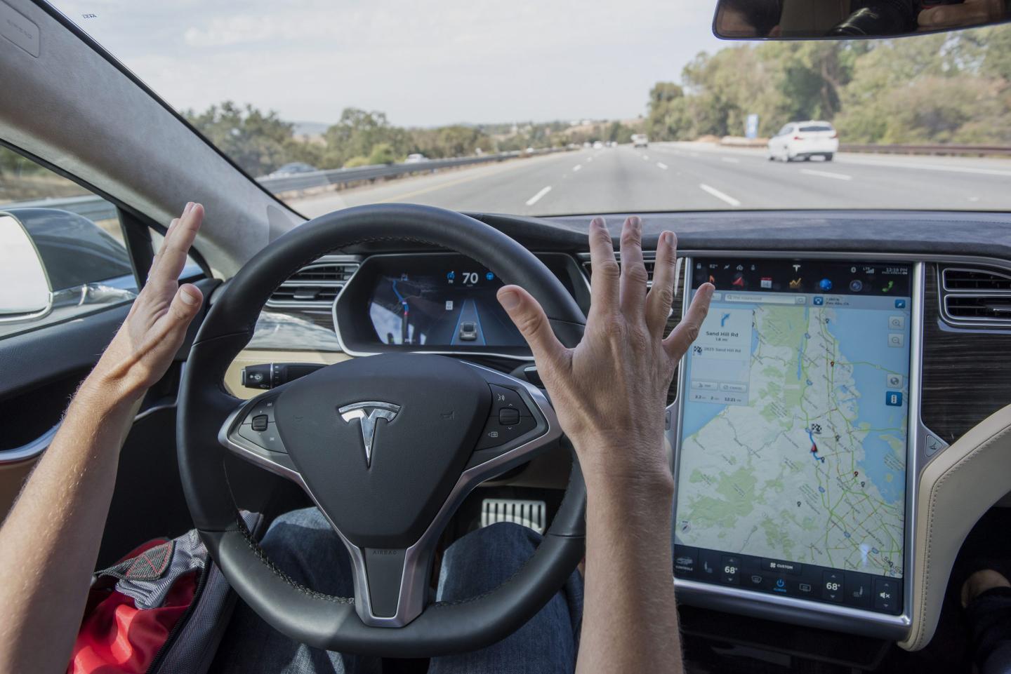 A person demonstrating hands-free driving in a Tesla
