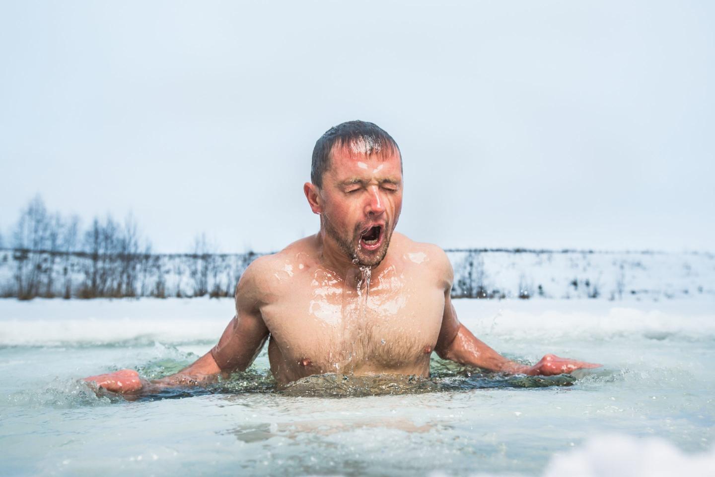 Man submerged up to his waist in icy water outdoors