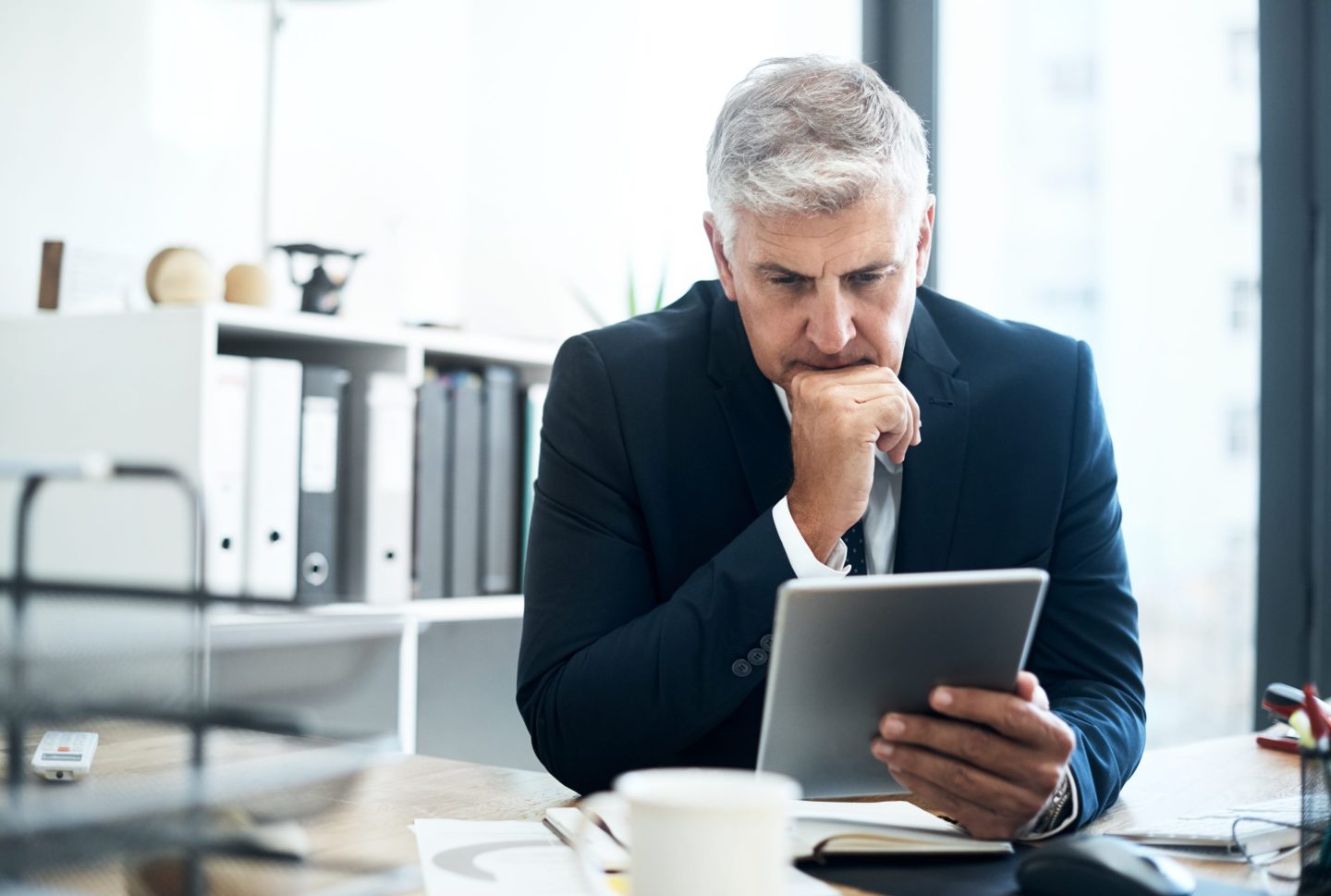 A businessman uses a tablet at his desk.