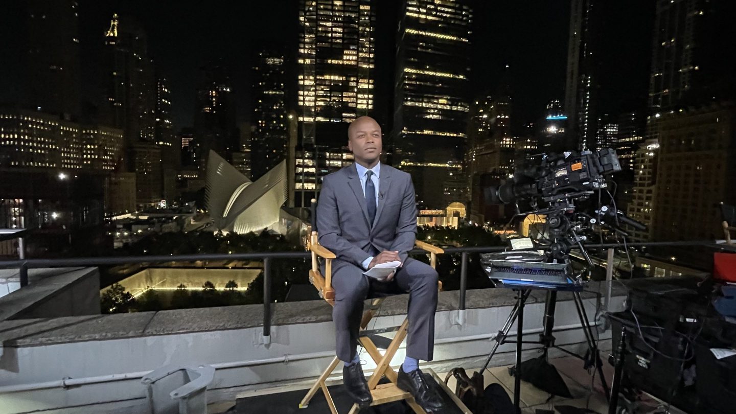 Kendis Gibson on set with nighttime cityscape behind him
