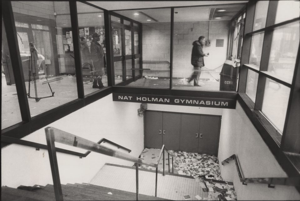 A narrow stairway leading to sets of closed doors is littered with flyers.