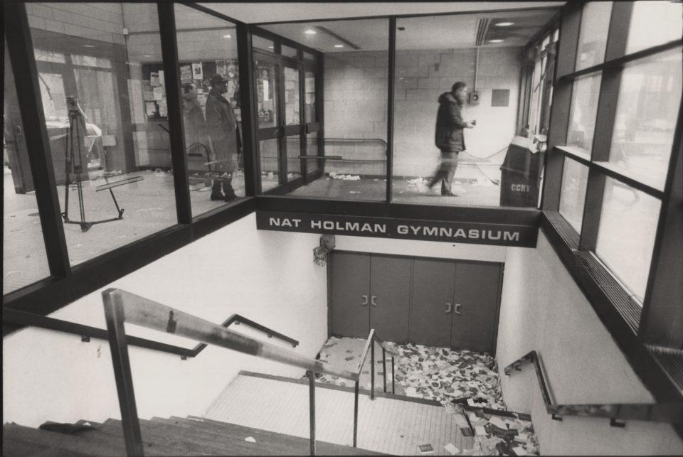 A narrow stairway leading to sets of closed doors is littered with flyers.