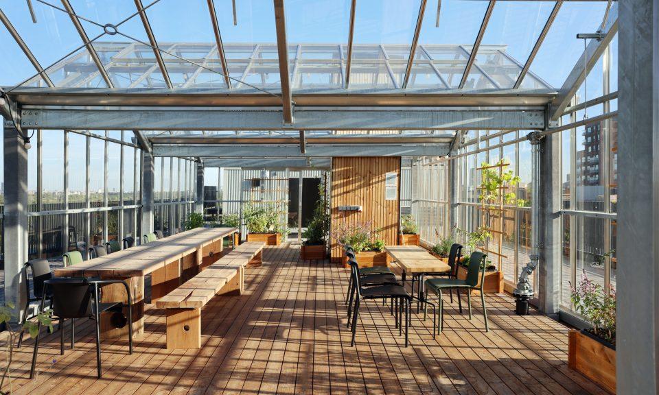 a rooftop with tables and chairs inside a glass structure