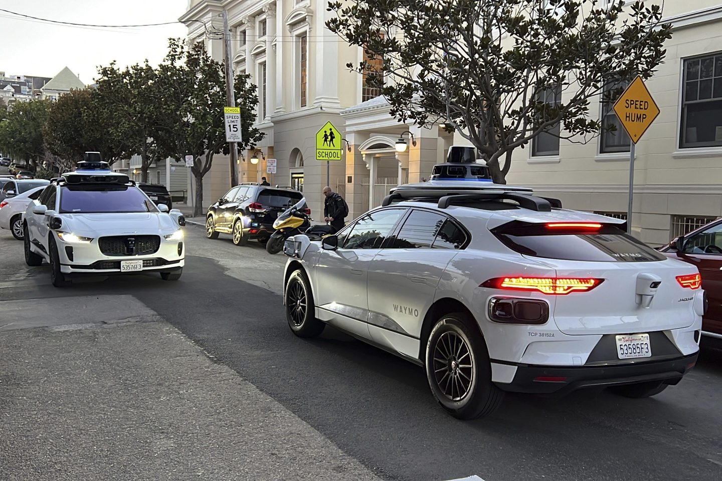 Two Waymo driverless taxis stop before passing one another on a San Francisco street on Feb. 15, 2023.