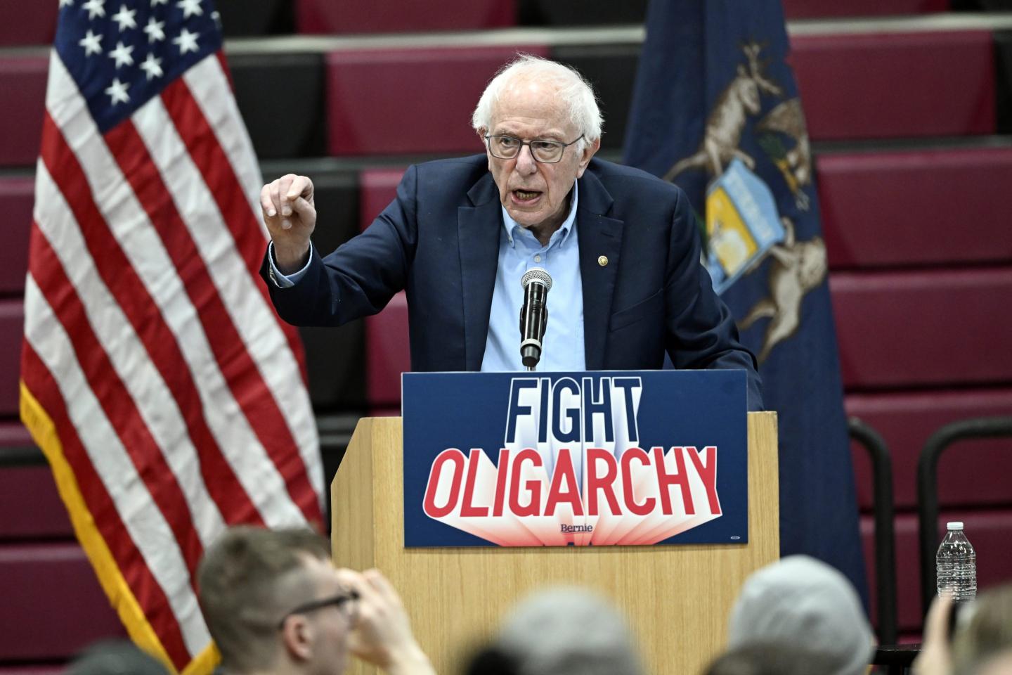Bernie Sanders stands in front of a podium at a rally against oligarchy