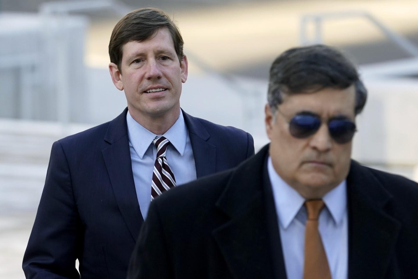 Former Sen. Brian Kelsey walks behind a man wearing sunglasses