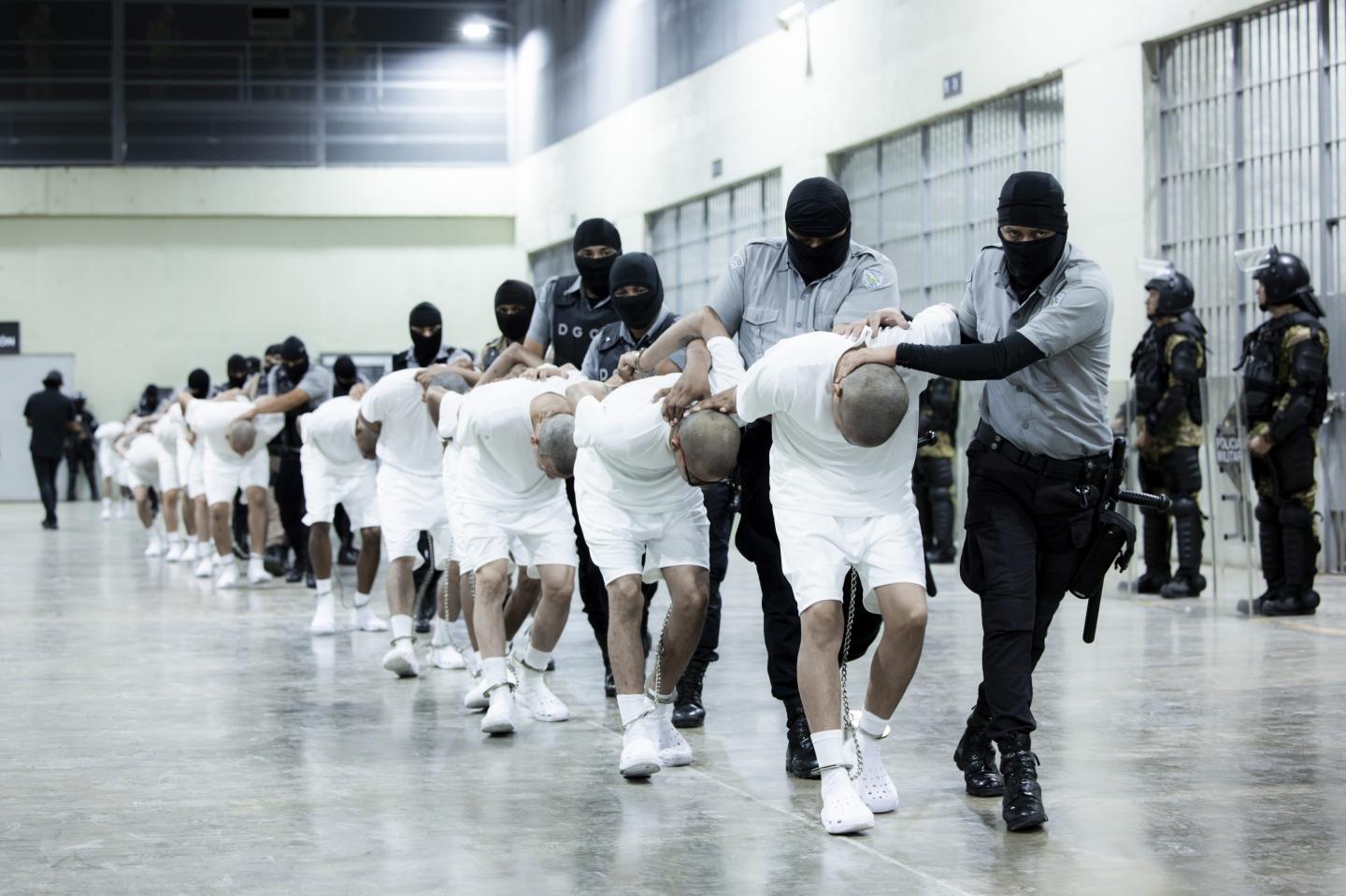 In this photo provided by El Salvador's presidential press office, prison guards transfer deportees from the U.S.
