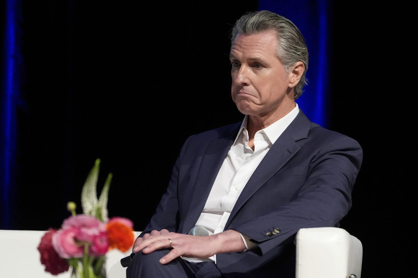 California Governor Gavin Newsom sits in a chair with a shocked look on his face