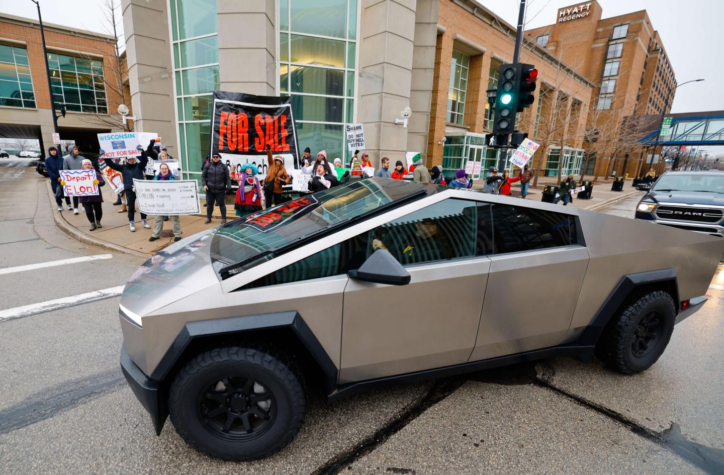 Protesters shout at a Tesla Cybertruck before a town hall with Elon Musk, on March 30, 2025, in Green Bay, Wis. 