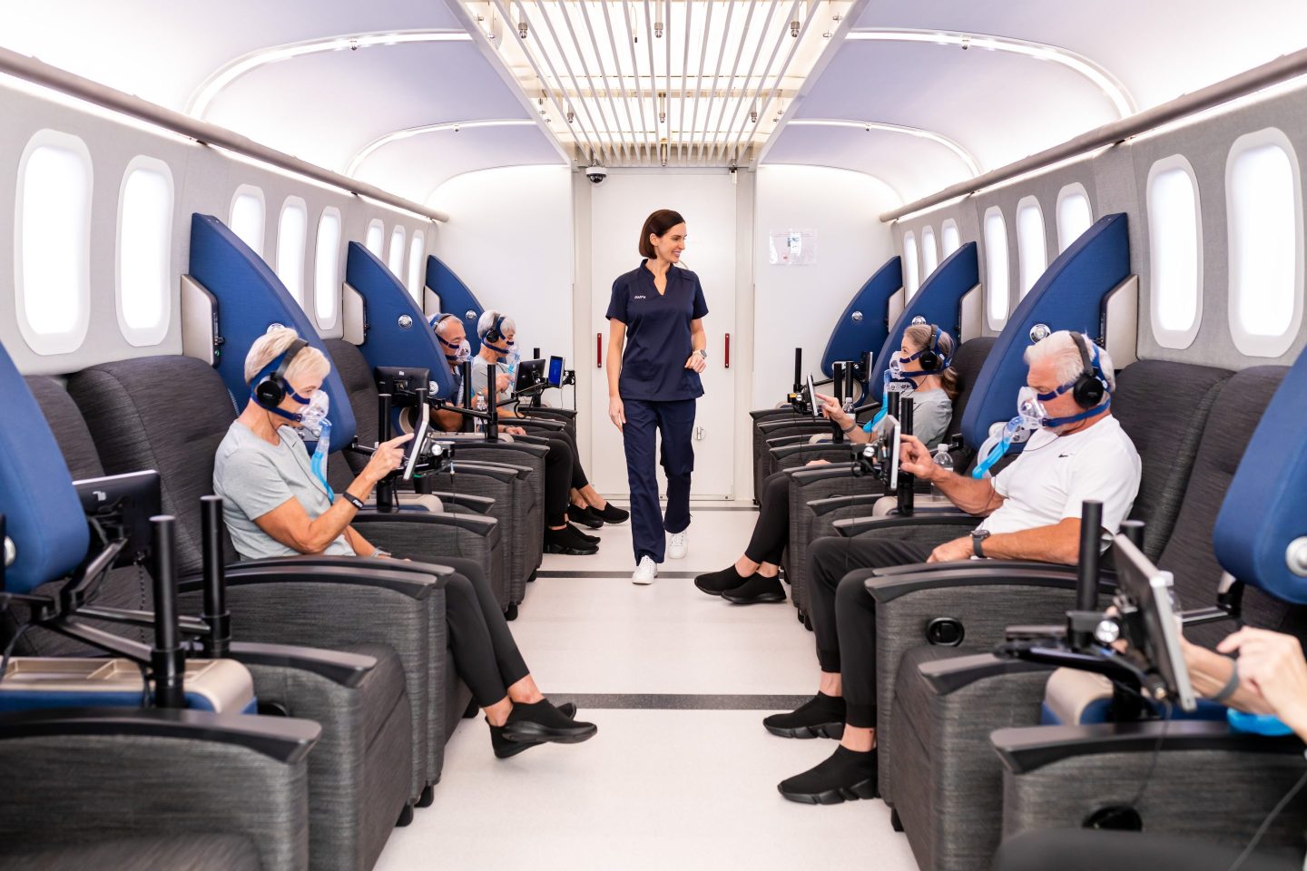 Patients sitting in a hyperbaric oxygen therapy suite with a technician standing among them