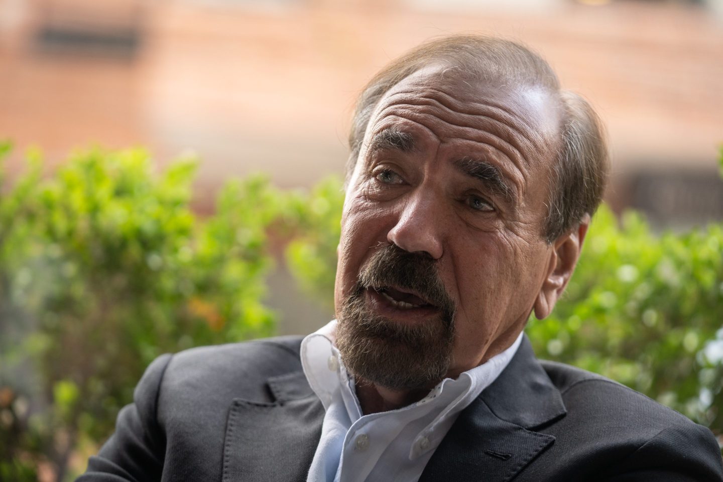 Jorge Perez speaking behind some bushes