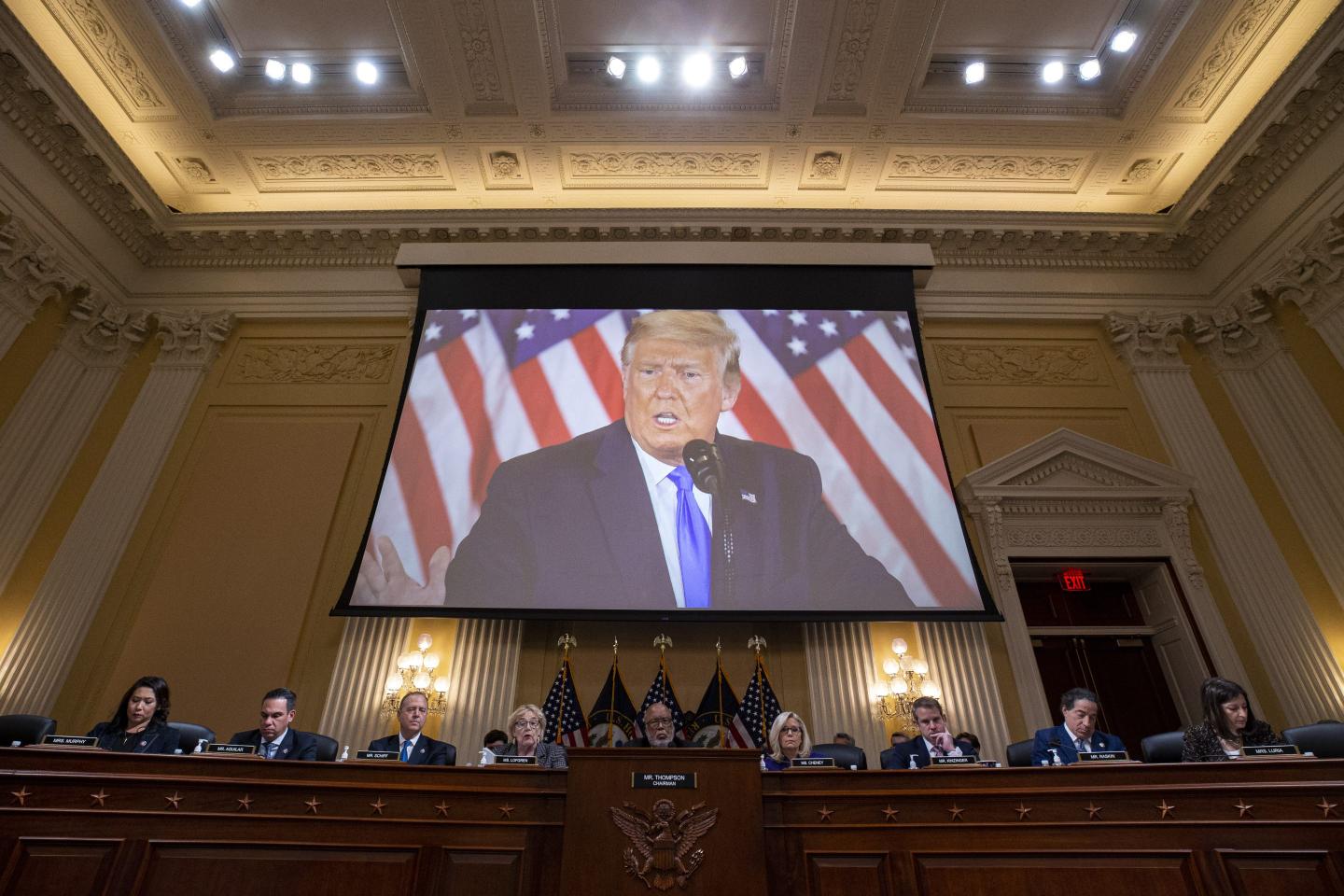 Trump's face displayed on a screen above a January 6th committee hearing