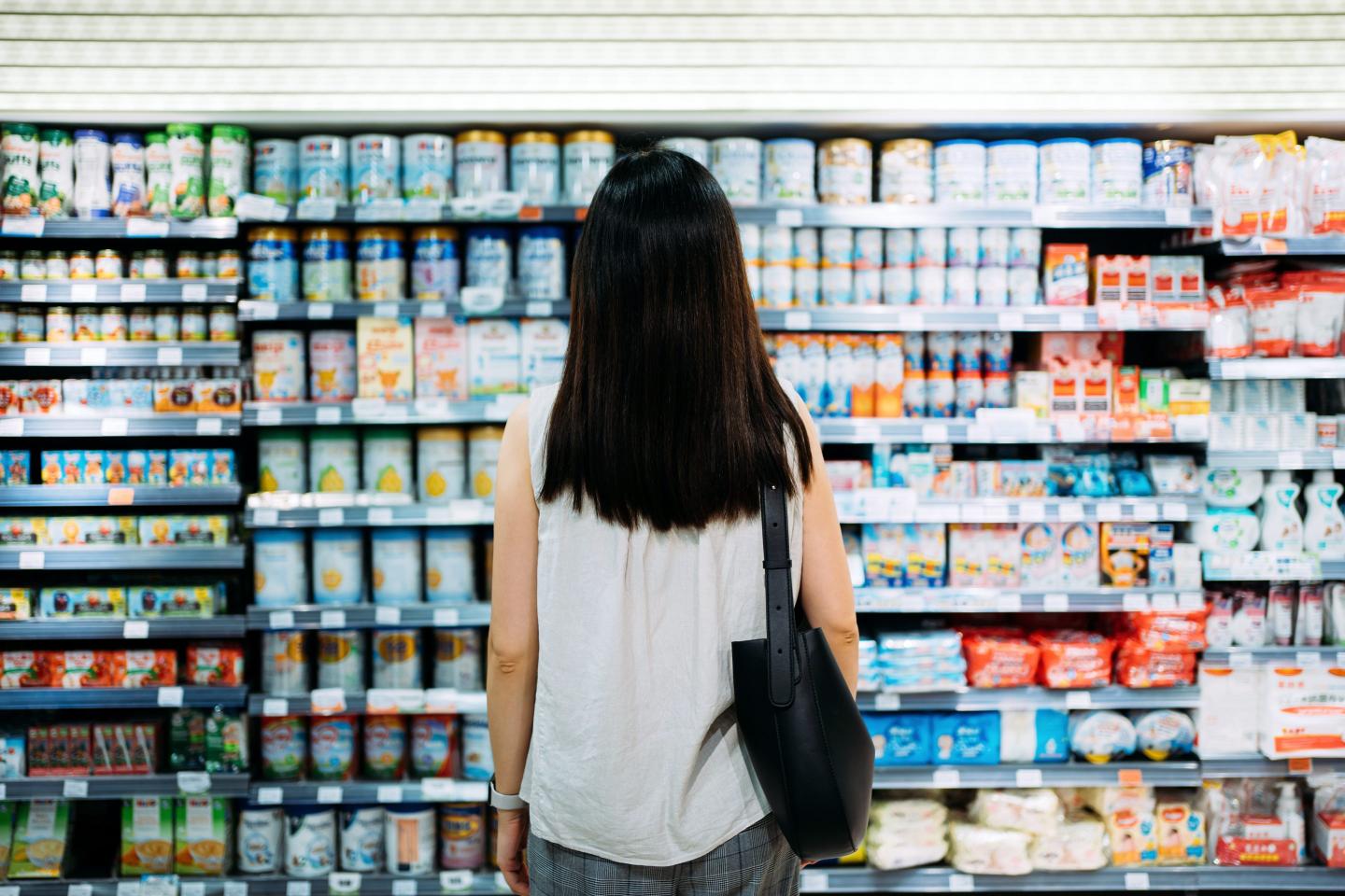 Woman standing in front of shelves of infant formula in a store