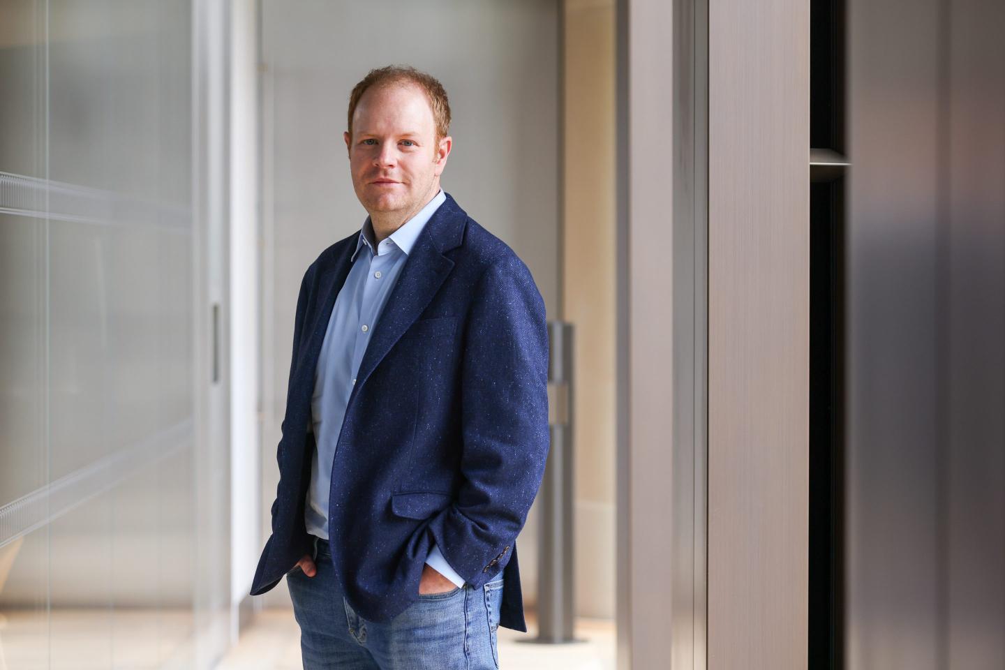 The Chief Executive Officer of Rippling, Parker Conrad, is standing in an office.