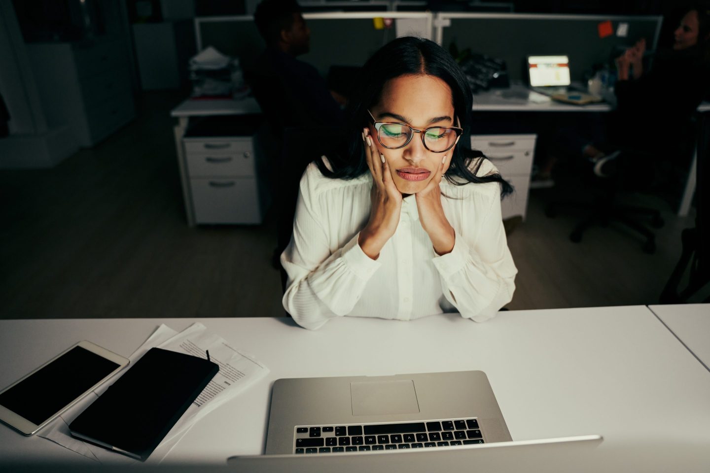 Anxious woman looks at laptop in a dark room