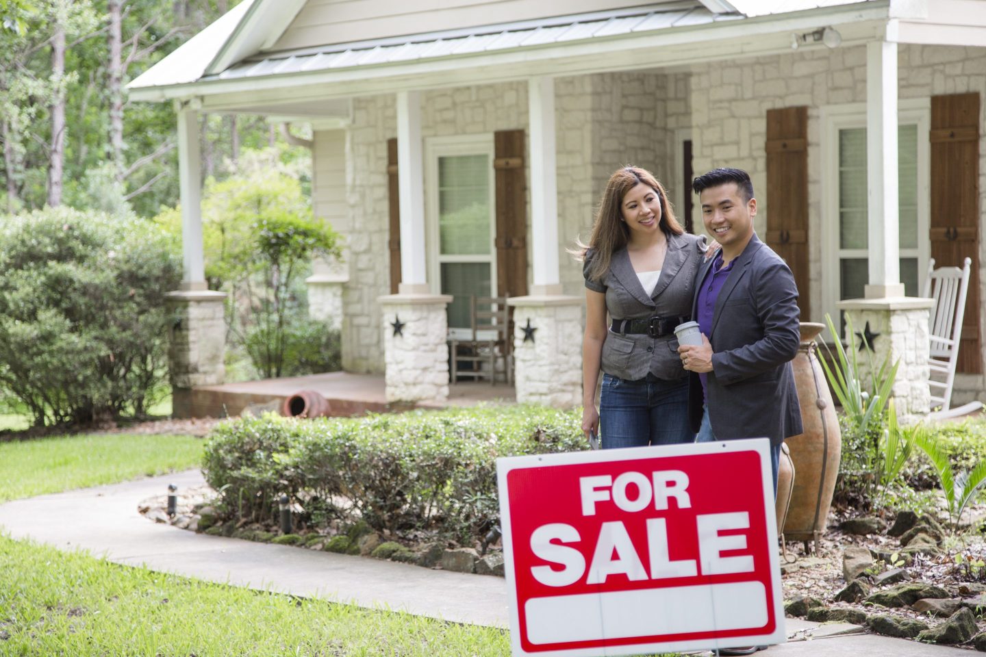 A couple in front of a home that is for sale.