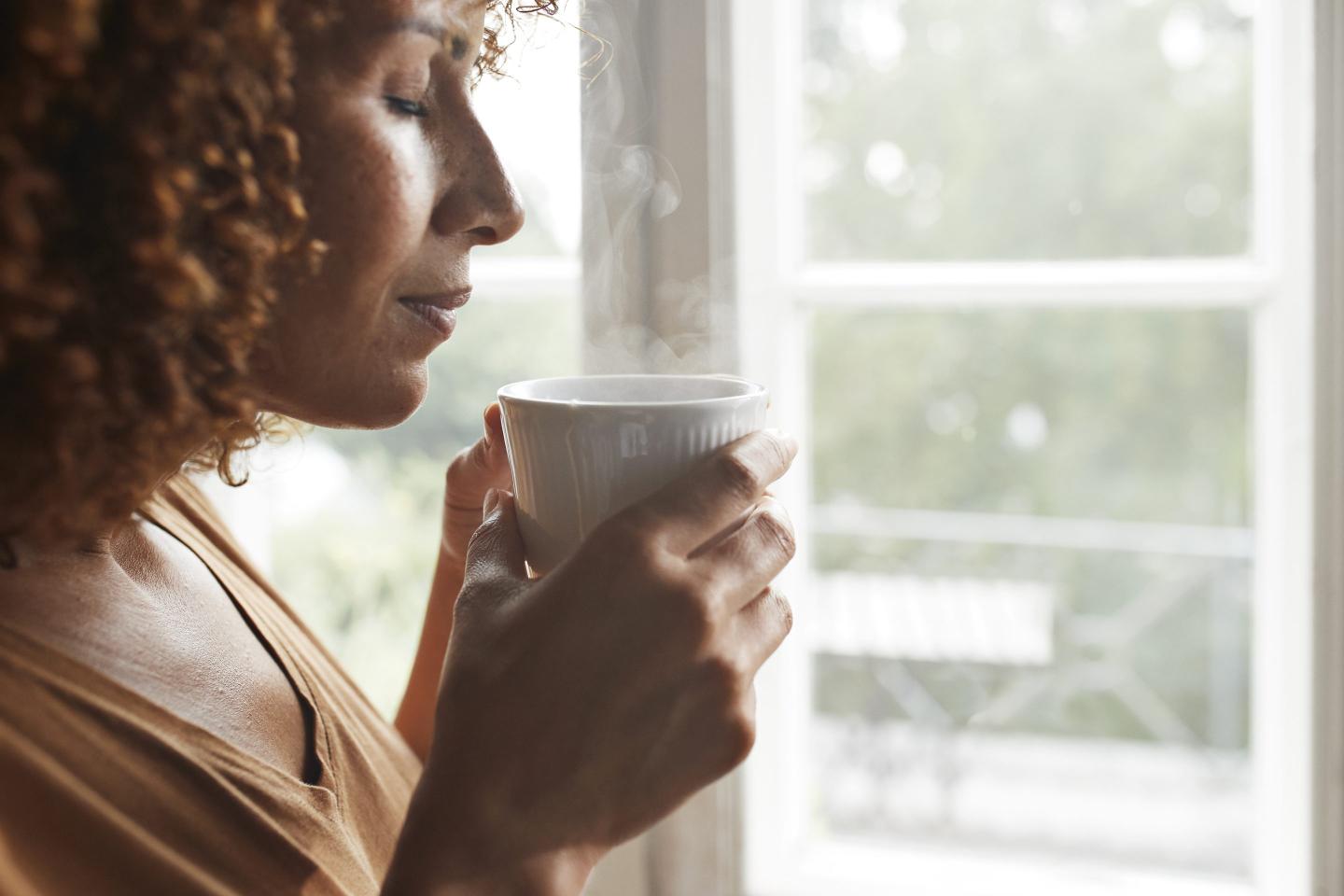 Woman holding a steaming cup of coffee