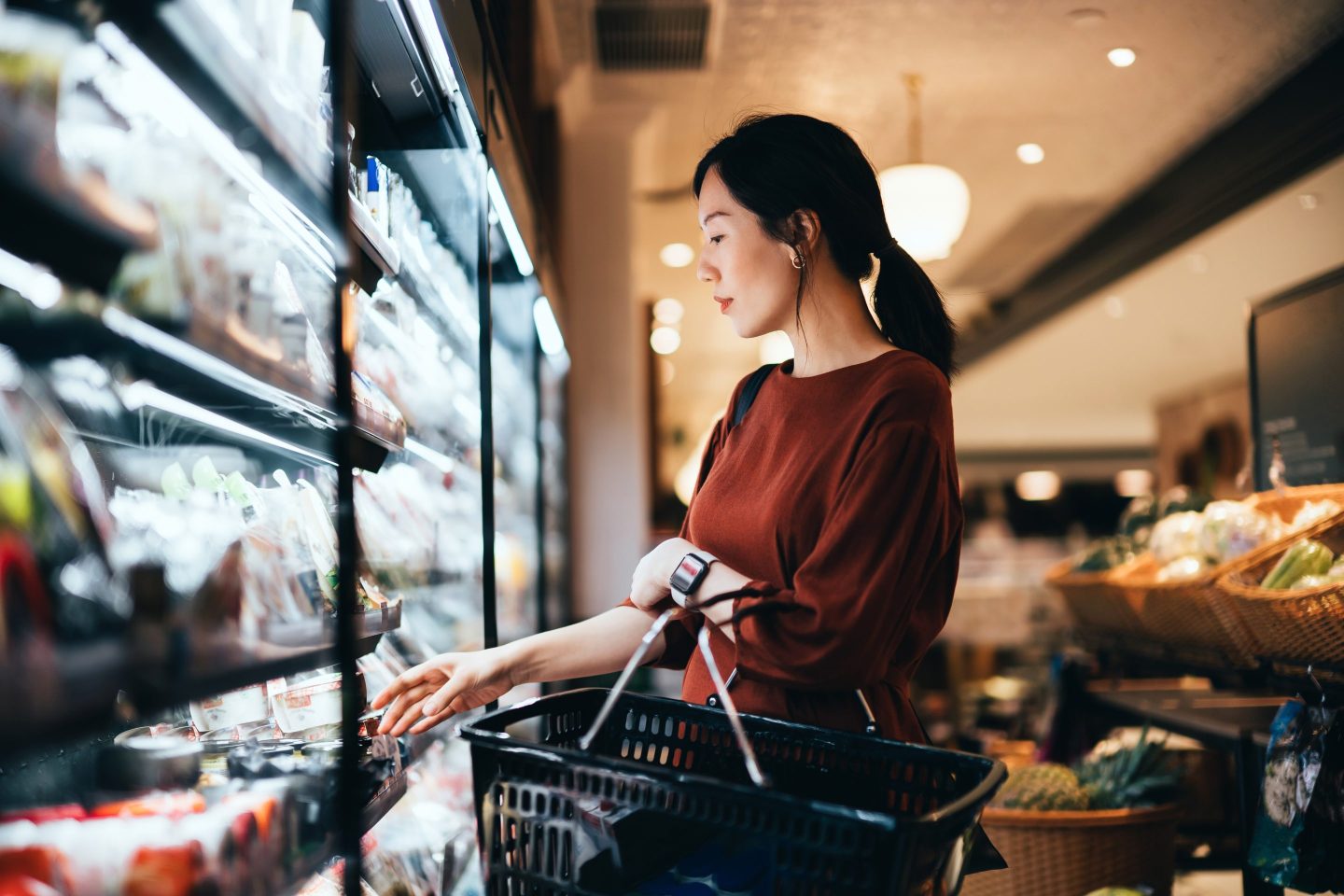 Woman in a supermarket holding a small shopping basket