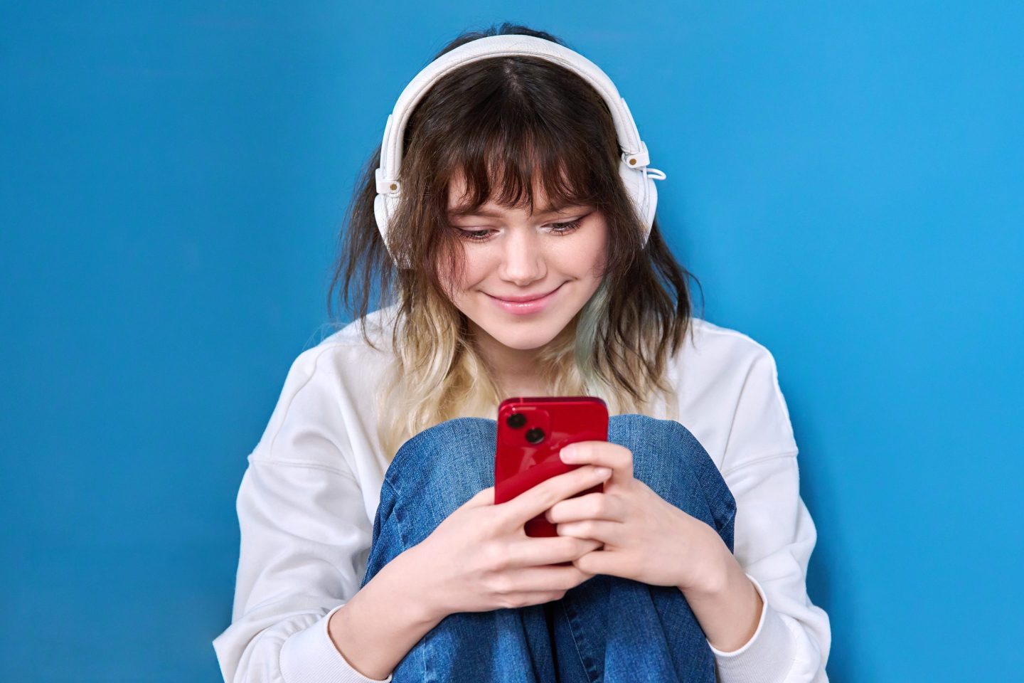 Teen girl wearing headphones and looking at her smartphone
