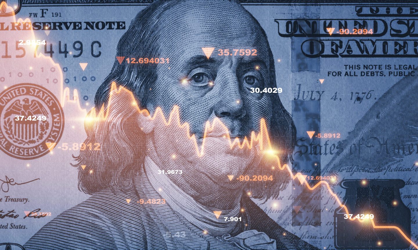 Artistic rendering of Benjamin Franklin on a $100 bill behind a graph showing downward movement