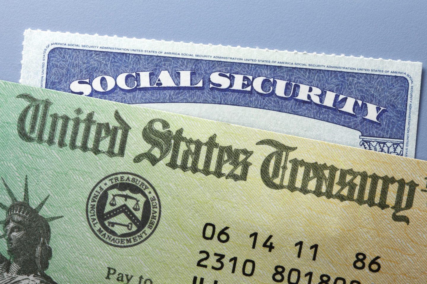 A United States Treasury government check rests on top of a Social Security card