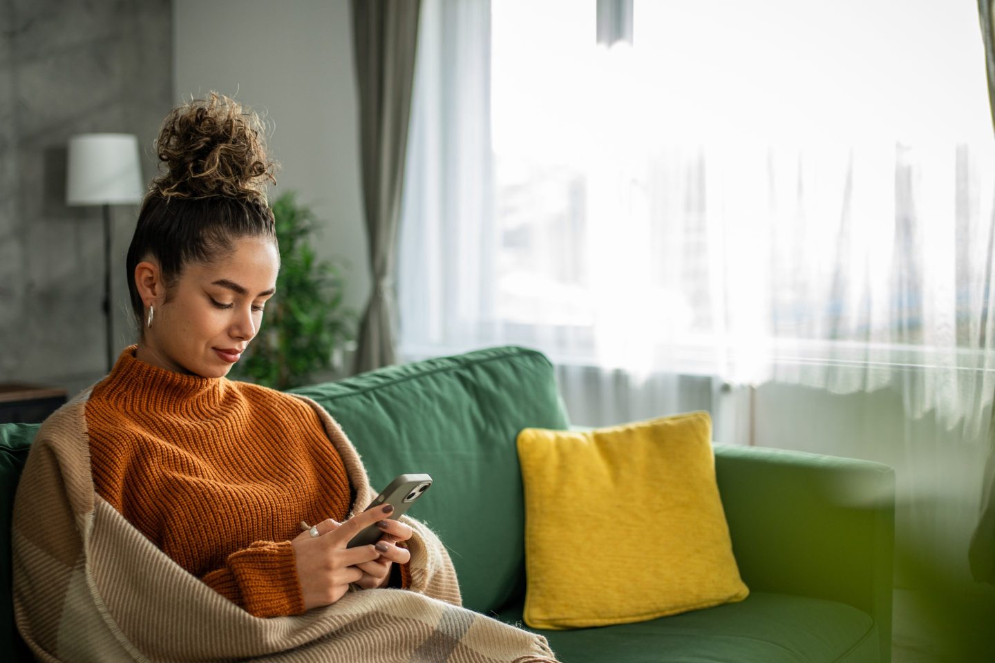 woman sitting on couch holding smartphone