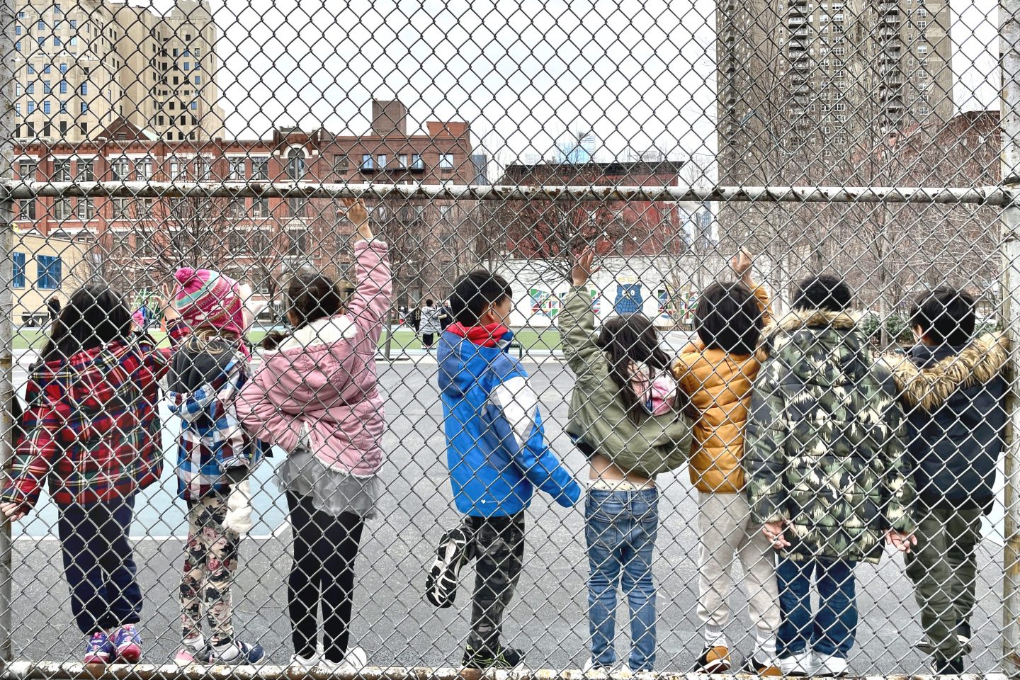 Children seen through a school playground fence in New York City
