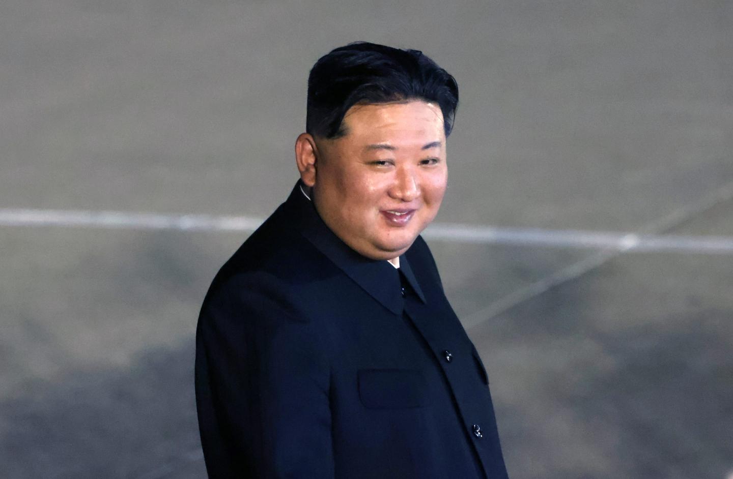 Kim Jong Un smiles at the camera as he walks outside.