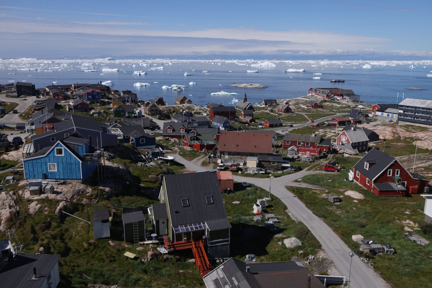Houses stand as icebergs drift by in Disko Bay on July 15, 2024 in Ilulissat, Greenland.