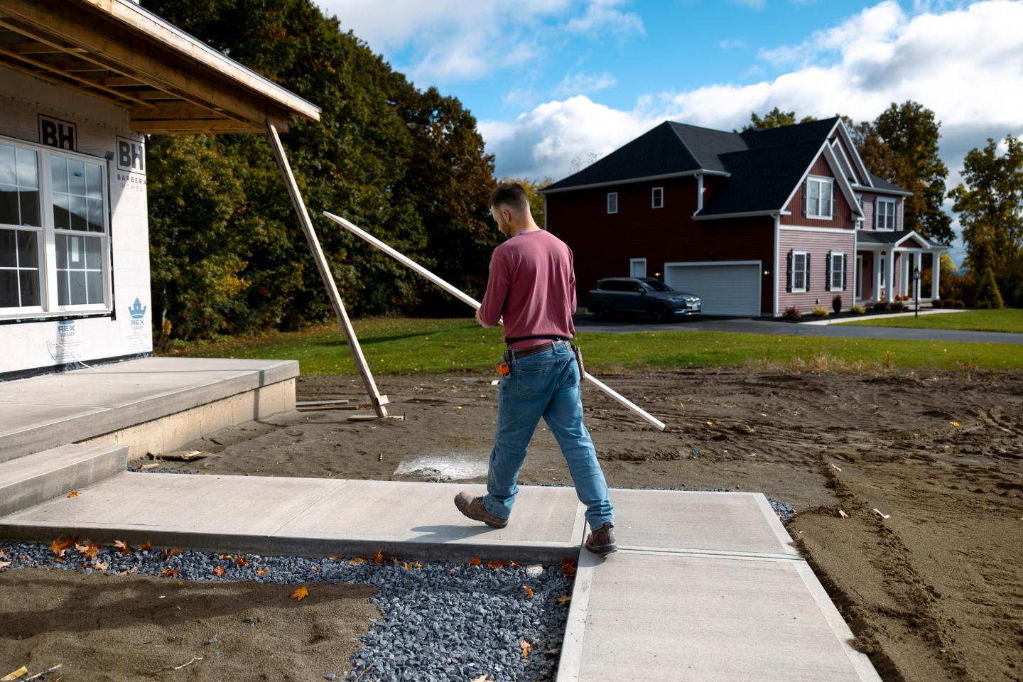 A worker carries a piece of trim into a home under construction