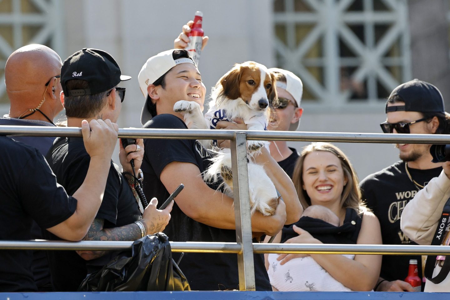 Shohei Ohtani holds a small dog surrounded by people