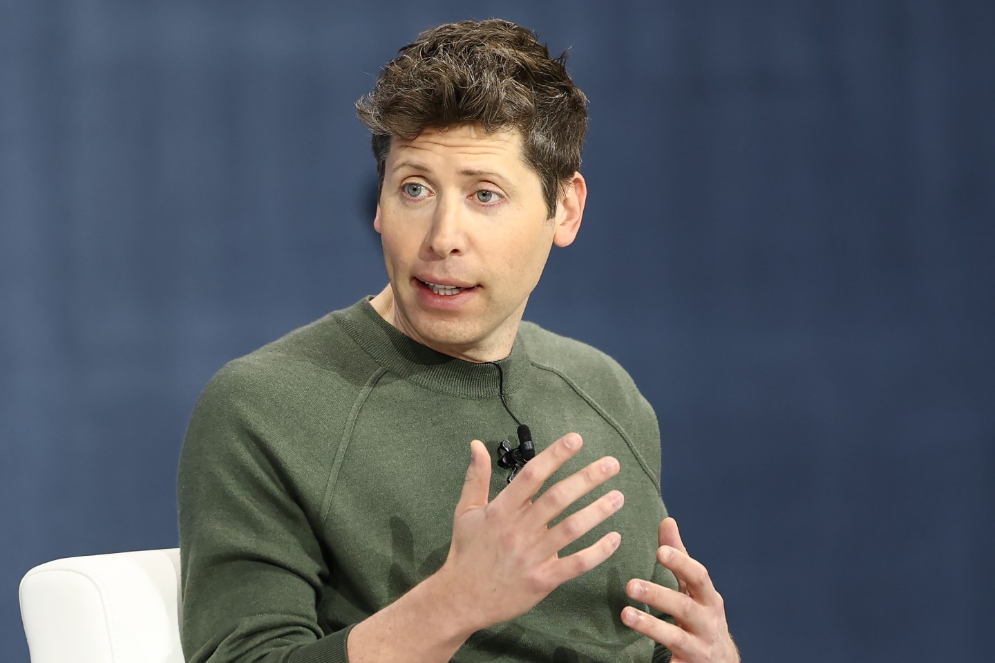 OpenAI CEO Sam Altman speaking and wearing a green top.