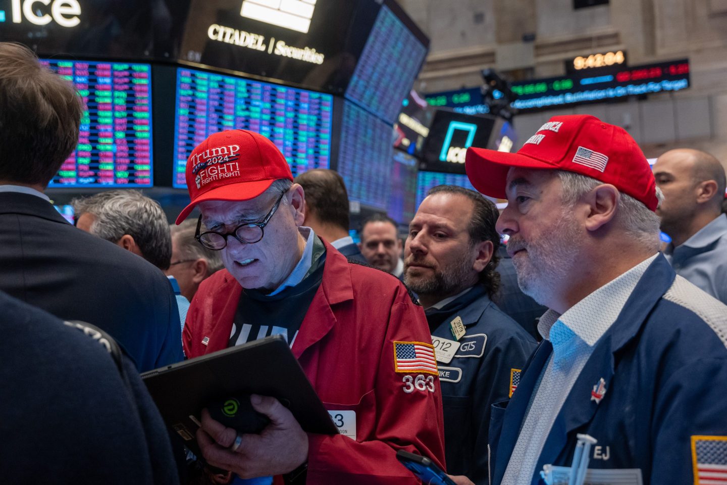 Traders wearing Trump memorabilia stand among a crowd on the floor of the New York Stock Exchange.